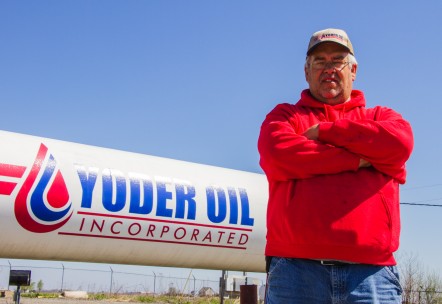 Yoder Oil sales representative standing in front of a propane tank wearing a red shirt